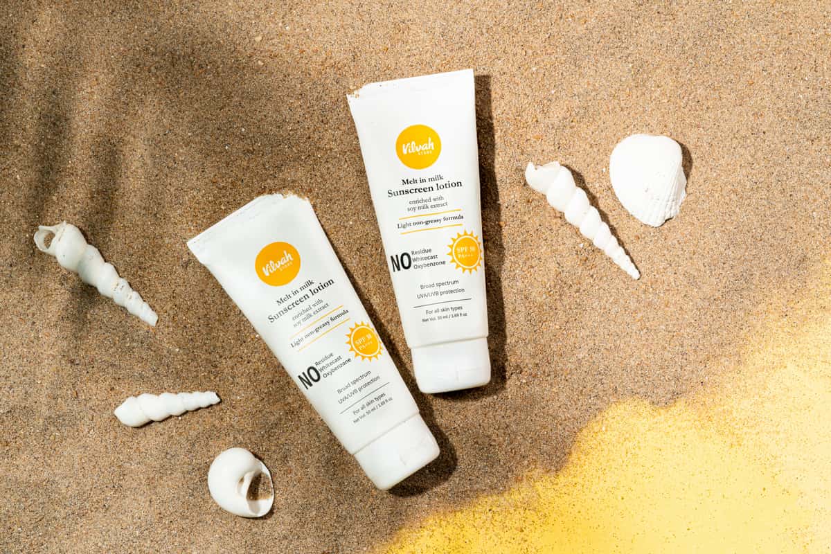 Two sunscreen bottles side by side on a sunlit ledge