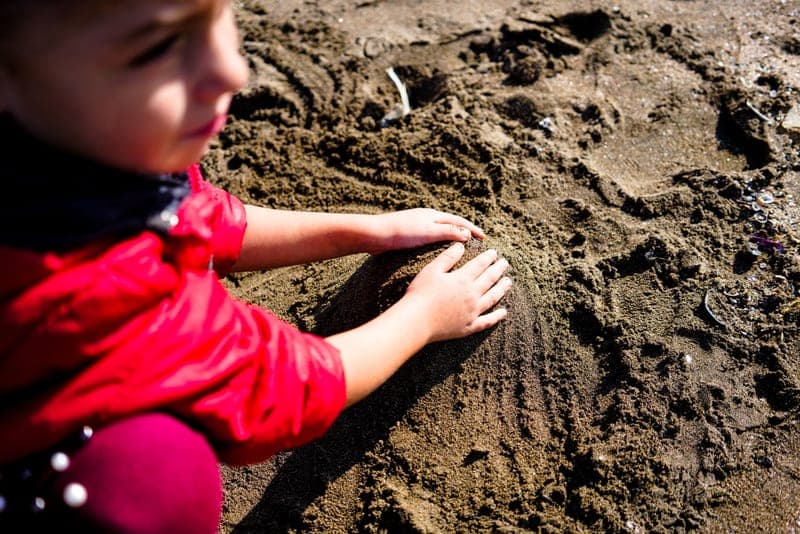 Mineral sunscreen lotion being applied to a child's arm outdoors